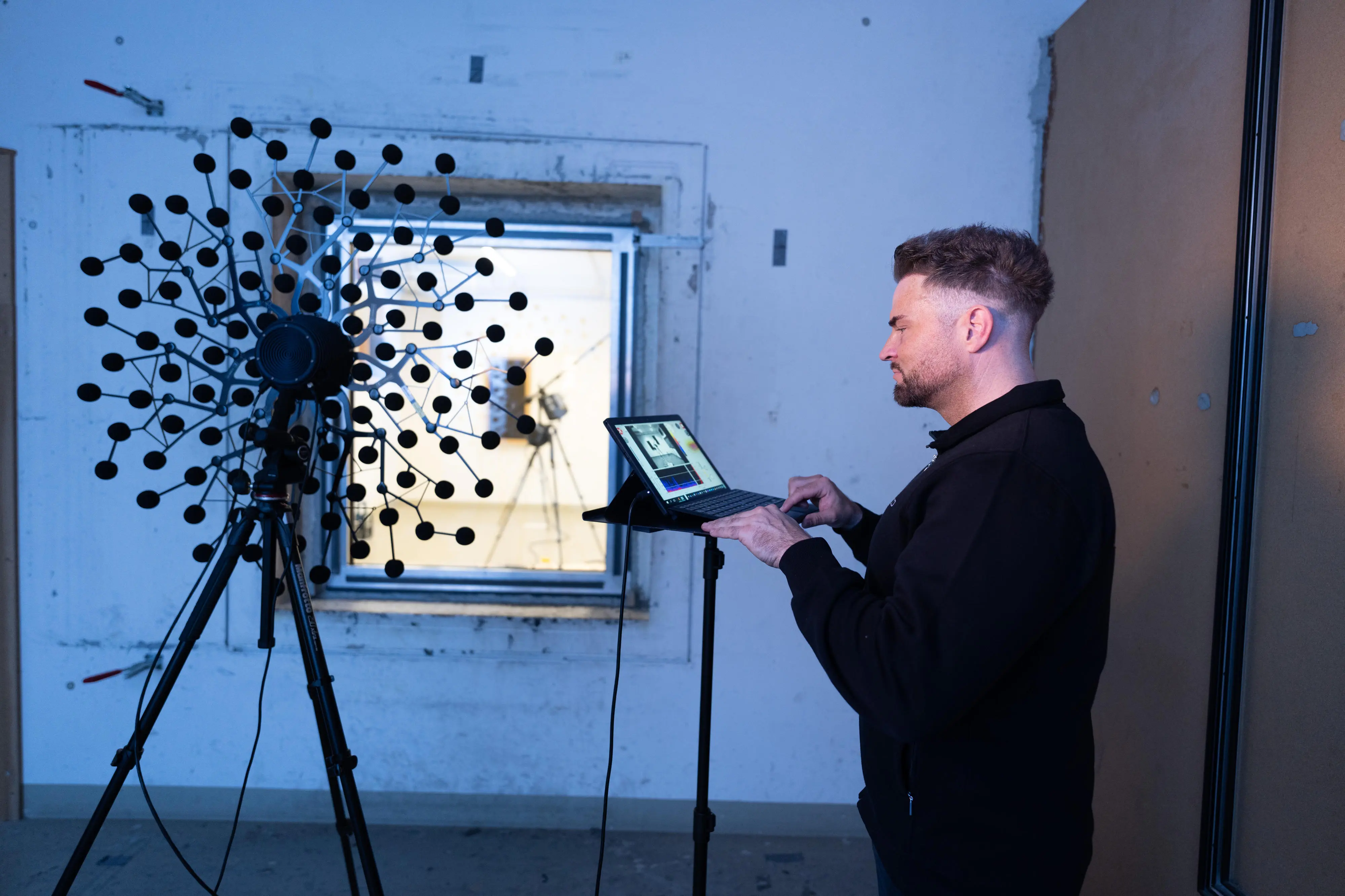 Prüfer mit Visualisierungssoftware und der akustischen Kamera vor Prüfobjekt