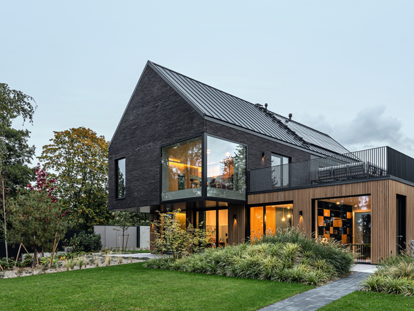 Villa mit großen Fenster und Schiebeelementen vom Garten aus fotografiert