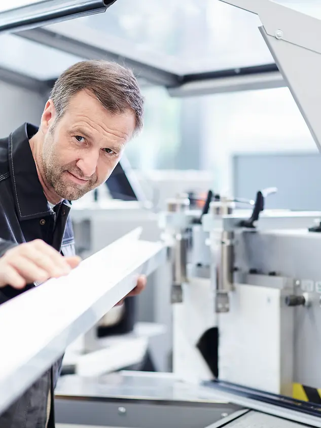 Mann jobber med en profil på verksted. Foto.