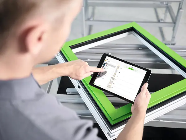 Mann betjener et nettbrett med vindusprofil synlig i bakgrunnen. Foto.