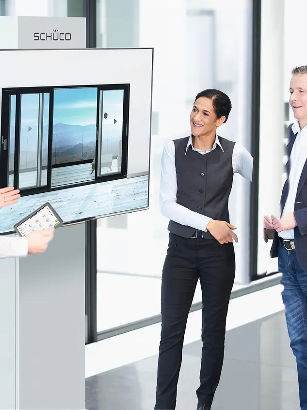 To menn og én kvinne stående foran et stort bilde av terrasseskyvedør. Foto.