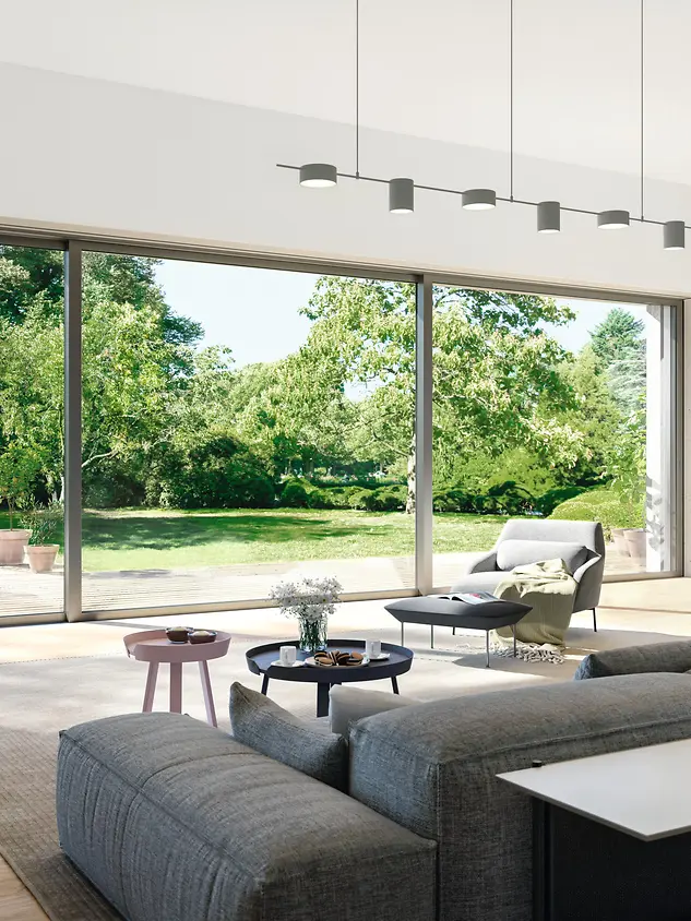 Ambiente living con scorrevole alzante Schüco in alluminio aperto su terrazza