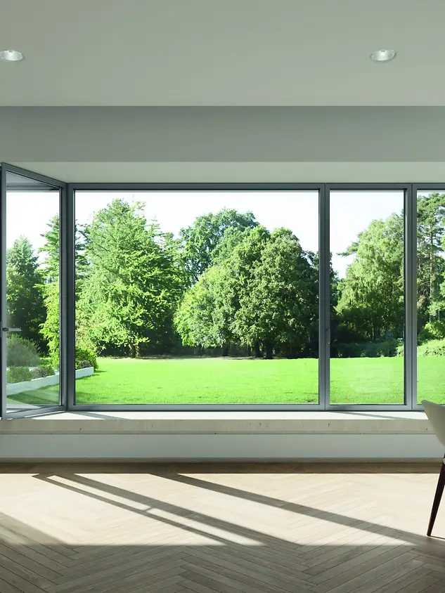 Interno luminoso con finestra panoramica Schüco AWS 75 PD.SI che si apre sul giardino, profili sottili e massima trasparenza