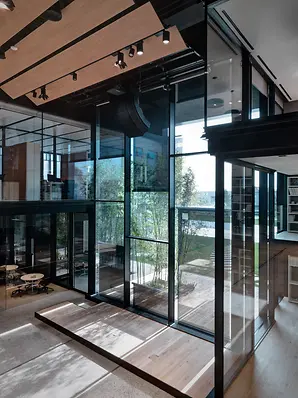 Interno luminoso di Theatro con ampie superfici vetrate, alberi integrati e spazi dedicati al lavoro