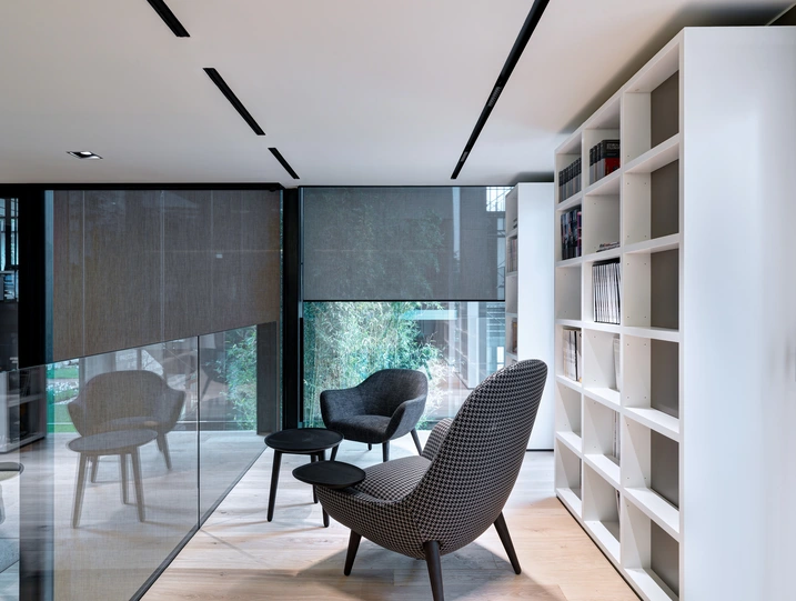 Area interna di Theatro con sedute, tavolino e librerie, illuminata da ampie vetrate
