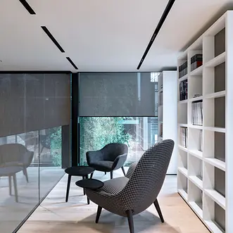 Area interna di Theatro con sedute, tavolino e librerie, illuminata da ampie vetrate