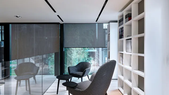 Area interna di Theatro con sedute, tavolino e librerie, illuminata da ampie vetrate