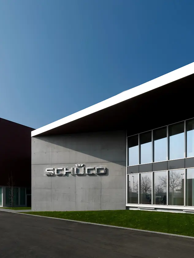 Vista esterna della sede Schüco Italia a Padova, con facciata vetrata e logo Schüco in primo piano.