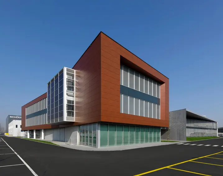Volume degli uffici della sede Schüco Italia con rivestimento in pannelli metallici color rame e ampie finestre vetrate.