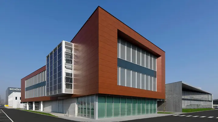 Volume degli uffici della sede Schüco Italia con rivestimento in pannelli metallici color rame e ampie finestre vetrate.