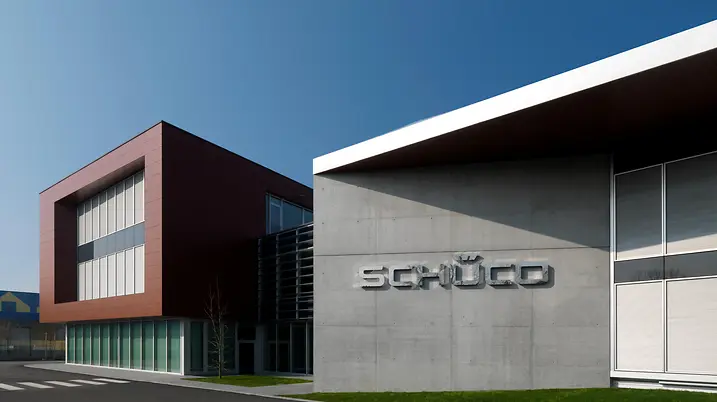 Ingresso principale della sede Schüco Italia, con ampia facciata vetrata e volume degli uffici