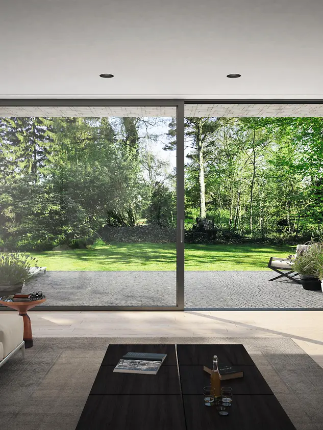 Ampia finestra scorrevole Schüco con vista sul verde, simbolo di prodotti sostenibili e ad alta efficienza energetica.