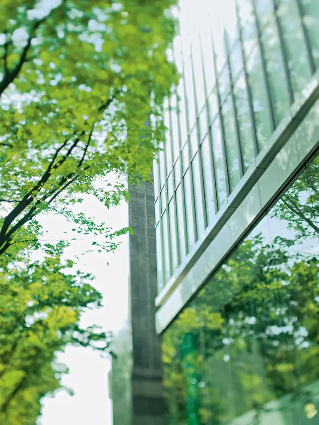 Facciata in vetro Schüco immersa nel verde che rappresenta l’approccio sostenibile Cradle to Cradle® all’architettura.