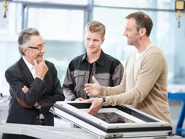 Tecnici e professionisti Schüco che discutono soluzioni per infissi in alluminio durante una sessione di consulenza in officina.