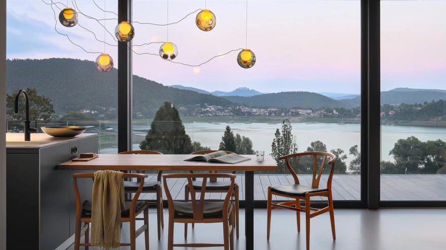 Essbereich mit Schüco Schiebesystem und weitem Blick von der Terrasse auf See und Berge