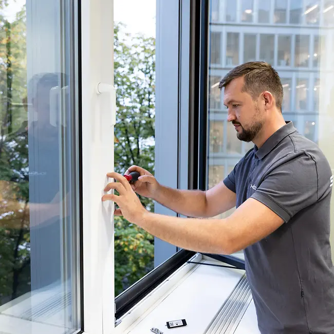 Tecnico Schüco Premium Partner che effettua la regolazione di una finestra in alluminio bianca