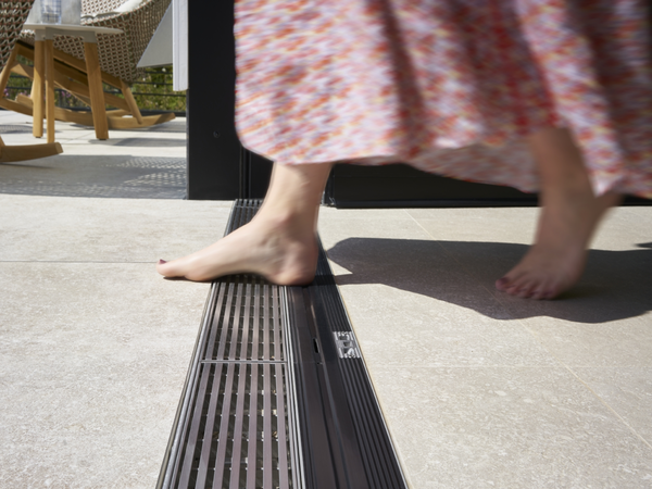 Person überquert barrierefreie Nullschwelle einer Schüco Schiebetür zur Terrasse