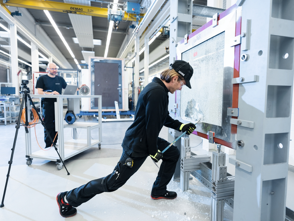 Person testet die Widerstandsfähigkeit einer Schüco Verglasung im Technologiezentrum