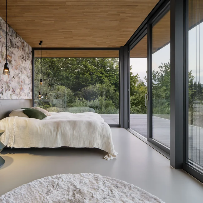 Schlafzimmer mit großen Fenster und Schiebeelementen von Schüco