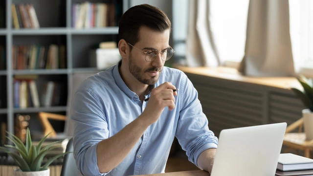 Person sitzt am Schreibtisch und arbeitet an einem Laptop