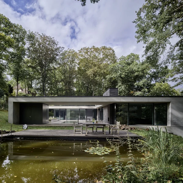Modernes Wohnhaus mit großen Schüco Schiebesystemen an einem Teich in ruhiger Naturumgebung