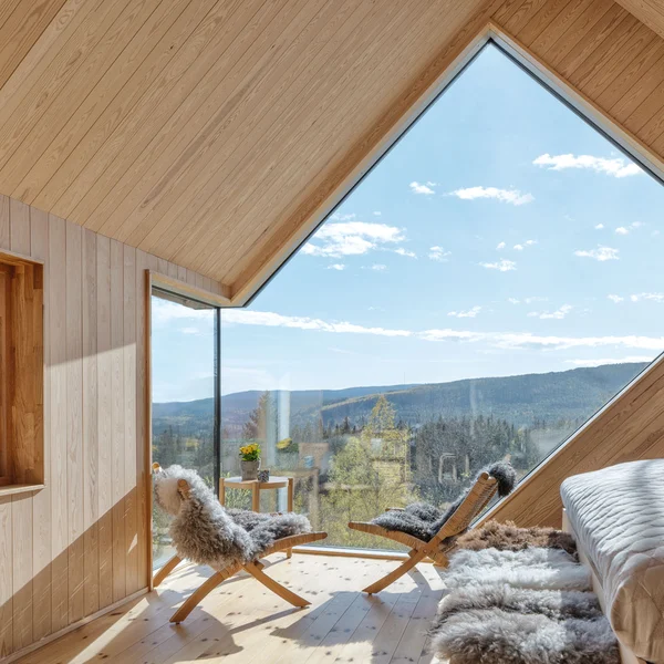 Wohnraum mit großflächigem Schüco Designfenster, Panoramablick und heller Holzarchitektur