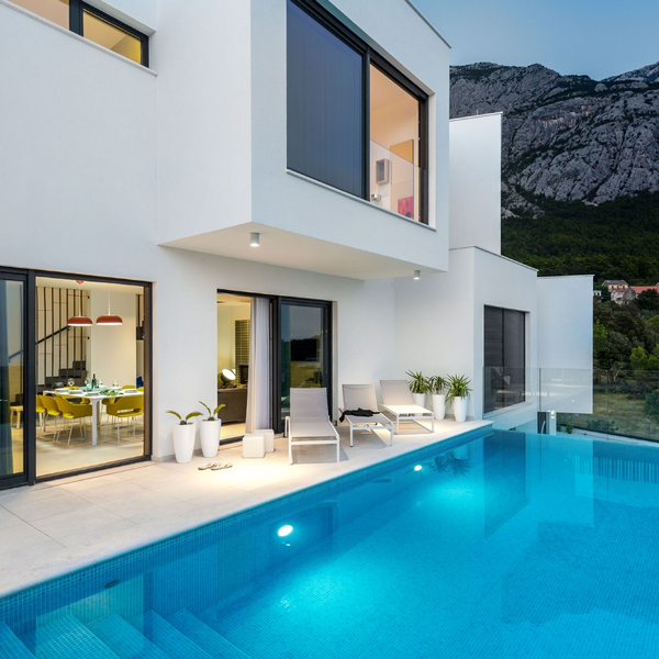 Modernes Wohnhaus mit Schüco Schiebesystemen, großen Fenstern und Pool vor einer Berglandschaft