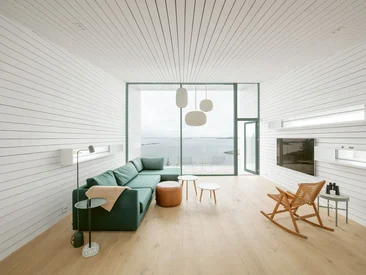 Minimalistischer Wohnraum mit großflächigen Schüco Fenstern, hellen Farbtönen und Seeblick