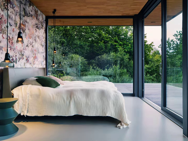 Modernes Schlafzimmer mit großer Fensterfront und Schiebeelementen von Schüco