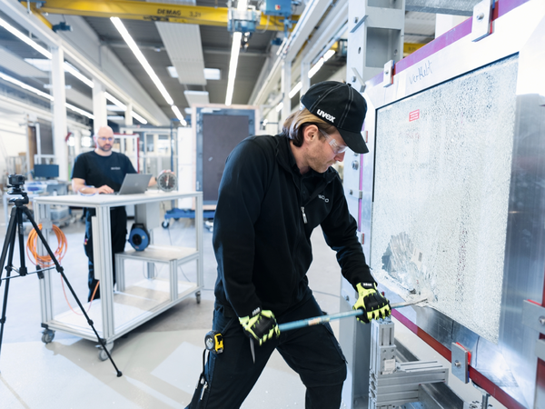 Person prüft mit einem Werkzeug die Oberfläche eines Schüco Fensters im Schüco Technologiezentrum