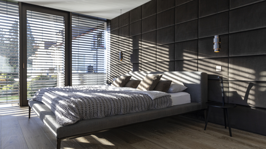 Modernes Schlafzimmer mit großflächigen Schüco Fenstern und außenliegendem Sonnenschutz